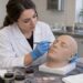 Estudiante con guantes practica maquillaje sobre una cabeza artificial de formación